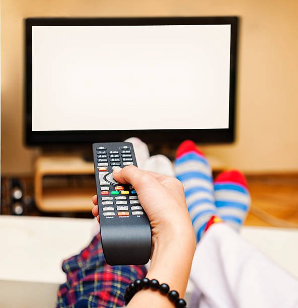 Close-up of a Hand Holding a Remote Control, TV showing white blank screen.